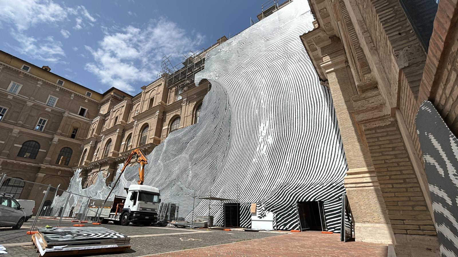 Una piattaforma aerea impiegata per l'installazione sulla facciata della Biblioteca Apostolica Pontificia delle stampe dirette su Dibond che compongono Diluvium di Jr